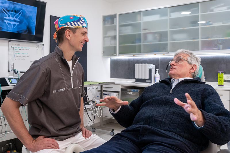 Dr. Gikic, an oral surgeon with SOTA Dental, talks about dental implants with a male patient.